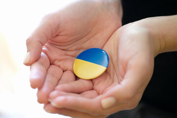 Female hands holding badge with flag of Ukraine closeup