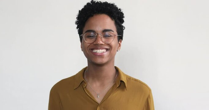 Headshot portrait happy overjoyed young Black woman look at camera with laughter isolated on white background. Pretty positive teen lady in glasses laugh in good joyful mood show white healthy teeth