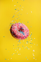 Donut levitating on a yellow background with decorative sprinkles.