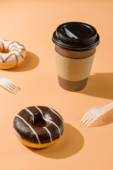 Donuts and a glass of coffee on a beige background. Takeaway food concept.