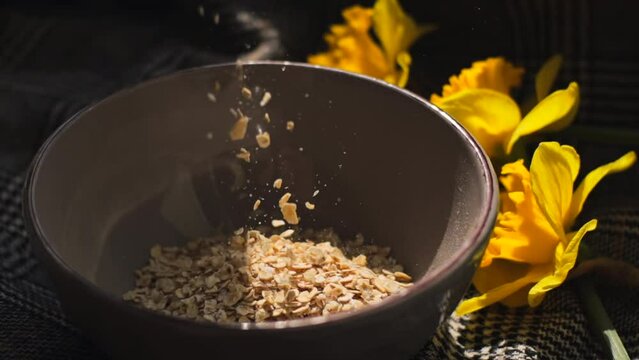 Pour oatmeal into a bowl.
Nearby are yellow flowers