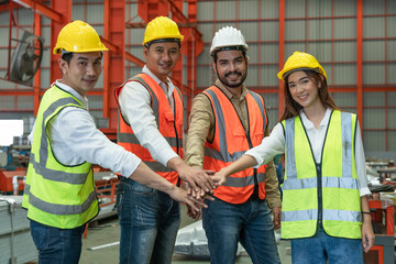 Group of Engineers smiling wear safety vests with helmets join hands to collaborate with team...