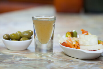 ginger shot served with olives and vegetable salad 
