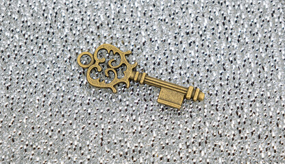 Bronze ornamental key with unique shapes and design on sylver metal shavings background