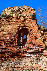 Spring landscape with red brick castle ruins, bare trees without leaves
