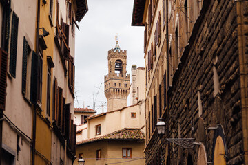 View of the medieval Palazzo Vecchio from the streets of Florence on a cloudy day. Houses wall framing. Florence famous landmarks