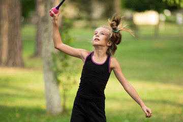 Obraz premium Girl doing exercise with clubs on rhythmic gymnastics training outdoors in summer in sports camp