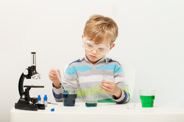 Boy five years old, experimenting with colored liquids. Chemical experiments of a little scientist boy of European appearance.