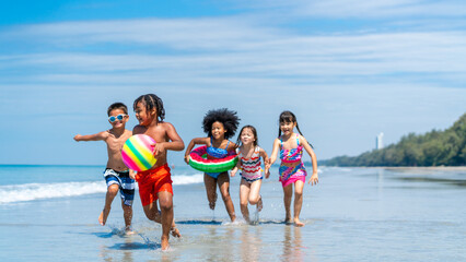 Group of Diversity little child boy and girl friends running and playing in sea water on tropical beach together on summer vacation. Happy children kid enjoy and fun outdoor lifestyle on beach holiday