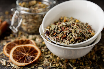 Herbal tea in a ceramic bowl and a glass jar on a black textural background. Detox and immunity...
