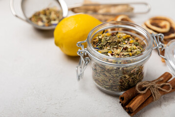 Aromatic herbal tea in a glass jar on a light gray background. Tea set with lemon, cinnamon, ginger and anise. Immune and vitamin tea. Cold drink. 