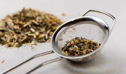 Dry herbal tea in a strainer for brewing on a gray cement background.Collection of useful herbs.Top...