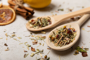 Wooden spoons with herbal tea leaves on a light background. Top view. Detox and immunity tea. Herbal collection of chamomile, mint, lemon balm. rosehip and pieces of dried fruits.