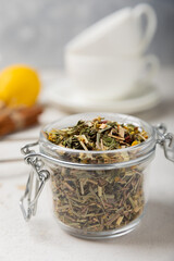 Fototapeta premium Aromatic herbal tea in a glass jar on a light gray background. Tea set with lemon, cinnamon, ginger and anise. Immune and vitamin tea. Cold drink. side view.
