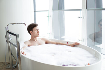 Young handsome man enjoying in the bathtub.