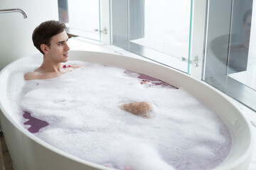 Young handsome man enjoying in the bathtub.