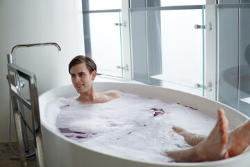 Young handsome man enjoying in the bathtub.