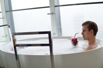 Young handsome man enjoying in the bathtub.