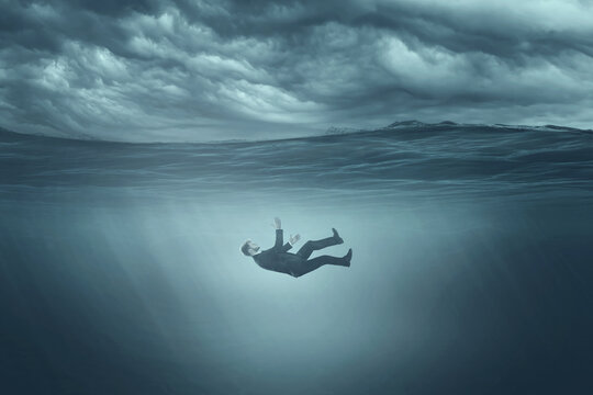 The human body sinks in gray water, sinks to the bottom, gray clouds. Depression, procrastination, despair, fear, apathy.