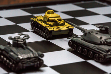 Toy tanks on a chessboard. The concept of military strategy.