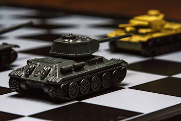 Toy tanks on a chessboard. The concept of military strategy.
