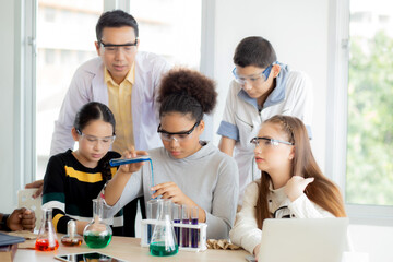 Young teacher teaching group student about science and test chemical for liquid in the lab of school, children studying and learning experiment science in the laboratory, education concept.