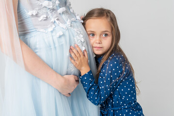 the little girl leaned against her mother who is pregnant, tenderly listening and listening....