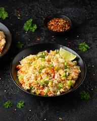 Prawn fried rice with eggs and vegetables in black bowl. Healthy asian food.