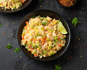 Prawn fried rice with eggs and vegetables in black bowl. Healthy asian food.