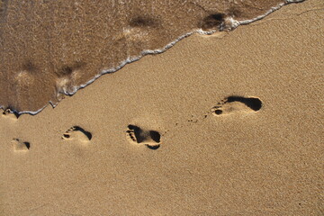 Footprints in the sand, white sand and approaching transparent water