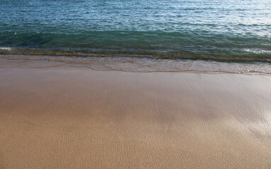 Sand and waves on a seashore, yellow sand and transparent water, isolated, no people
