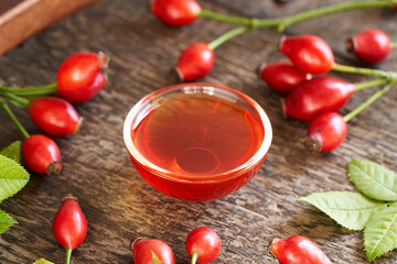 A bowl of rosehip seed oil with fresh rosehips - healthy cosmetic oil