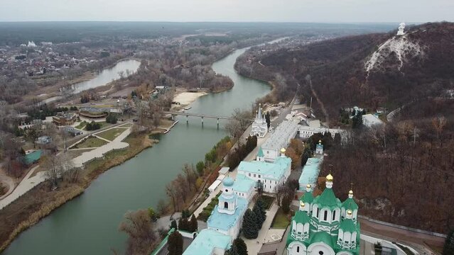 Panoramic aerial view from drone of Sviatohirsk Lavra chalk cave monastery, bridge over Seversky Donets river with autumn forest on riverbanks and Sviatohirsk village, Donetsk region,Ukraine