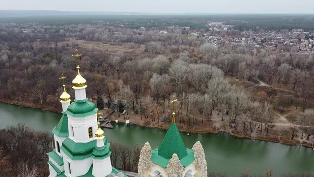 Domes of St. Nicholas Church of  Sviatohirsk Lavra with crosses at top aerial view from drone. Seversky Donets river and village of Sviatohirsk in background. Donetsk region, Ukraine