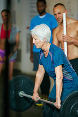 Nothing is going to happen in your comfort zone. Shot of a senior woman lifting weights while a...