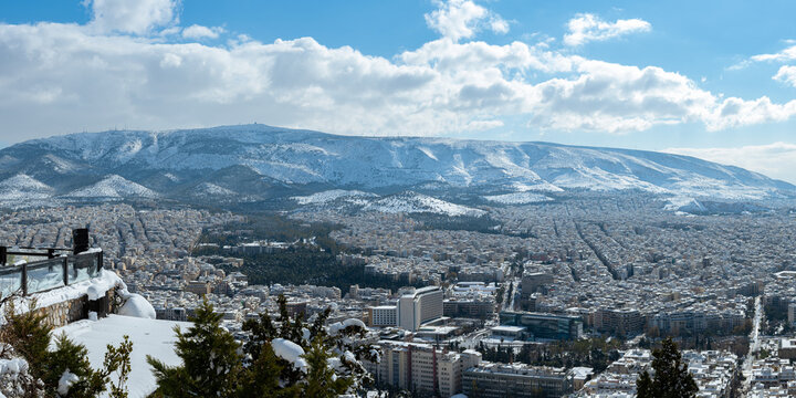 Panoramic view of mountain Hymettus (Ymittos) mountain and Athens cityscape covered in snow from Lycabettus hill