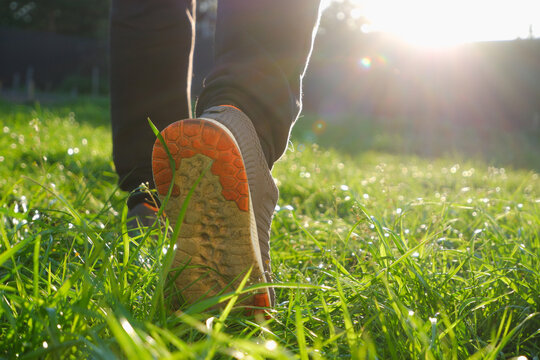 A Man In Sneakers Walks On Green Grass. Sport. Spring. Low Angle Back Shot. Man Feet Running On The Steps