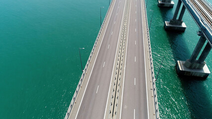 Flight above new white bridge with moving vehicles. Action. Breathtaking marine landscape with a...