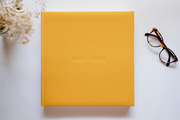 Composition with a wedding or family photo album, made of natural yellow linen fabric on a white...