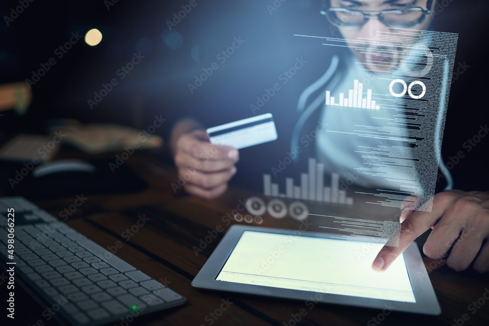 Poster Credit card fraud - its a risk and reality. Shot of a young hacker using a digital tablet to commit credit card fraud in the dark.