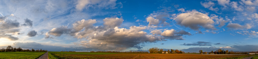 Eine Gewitterwolke in einem dramatischen Wolkenhimmel im Abendlicht der Sonne zieht mit ihren...