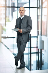 I use my tablet instead of my laptop for presentations. Shot of a mature businessman using his digital tablet at the office.