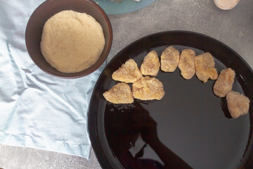 Chicken nuggets in breadcrumbs in a black cast-iron pan for baking