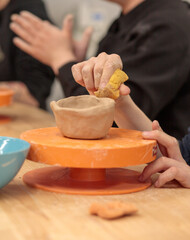 Art therapy. A person with a muscle disease makes a cup on a potter's wheel. Hands. Selective focus
