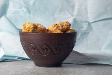 Ready-made homemade nuggets in a brown clay bowl on a blue napkin background