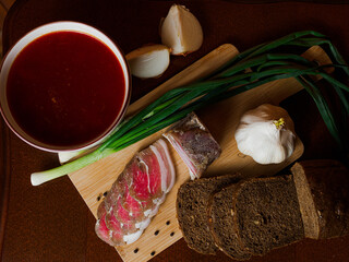 Delicious tender bacon with onions and bread on a wooden board in the house