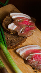 Delicious tender bacon with onions and bread on a wooden board in the house