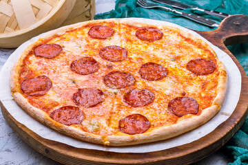 Pepperoni pizza on wooden board on grey table