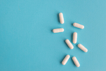 White capsule pills on a blue background. Medical background with copy space for text.