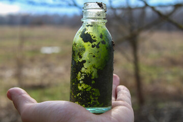 Glass bottle in hand with dirt inside
